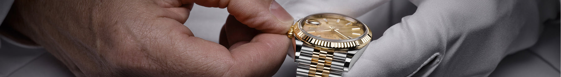 A man with one white glove on is adjusting the time on a Rolex as part of its service