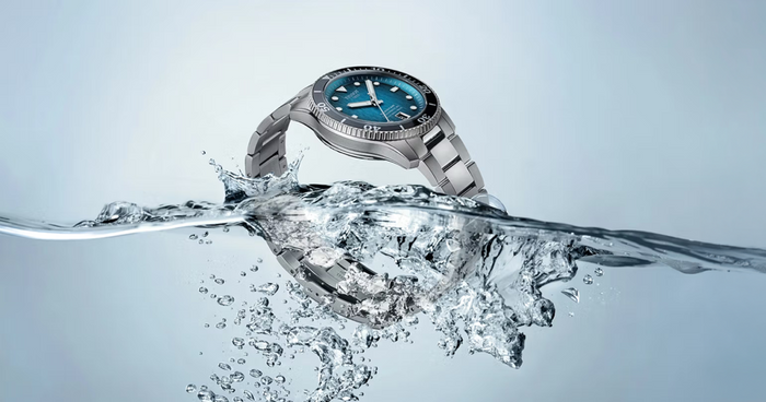 Tissot Seastar dive watch on a steel bracelet breaking the surface of the water in a burst of spray