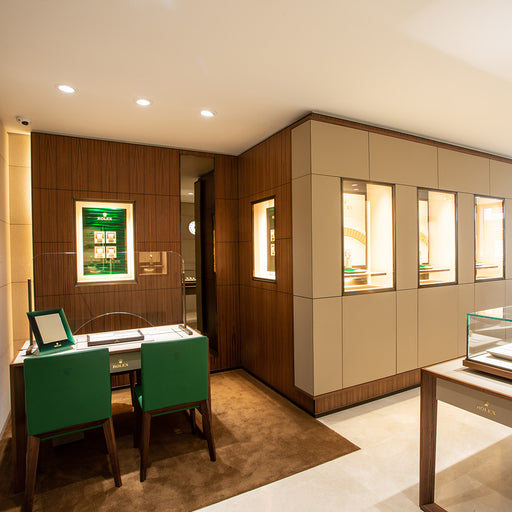 The Rolex showroom at Michael Spiers in Plymouth. A desk for viewing Rolex watches can be seen on the left with 2 chairs with Green leather. Jewellery can be seen in glass cabinets.